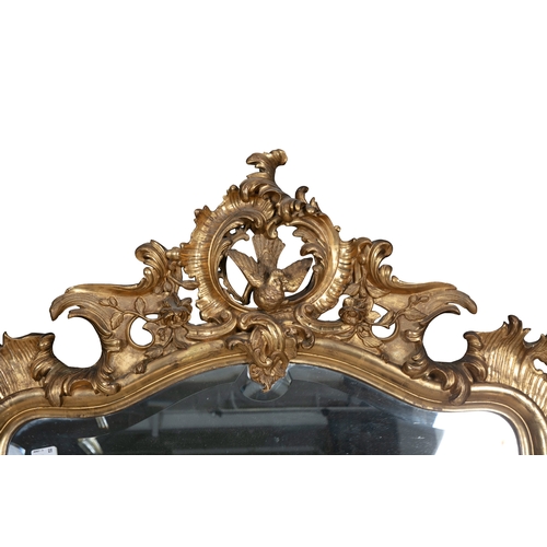 399 - A LARGE VICTORIAN GILTWOOD MIRROR,  of shaped rectangular form, the arched bevelled glass plate with... 