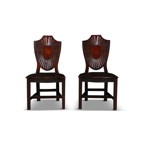 65 - A PAIR OF GEORGE III MAHOGANY SHIELD BACK HALL CHAIRS   each solid panel back with inlaid crest and ... 