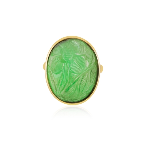 135 - AN EMERALD RING  Of foliate design, the oval-shaped carved cabochon emerald weighing approximately 3... 