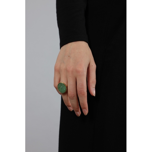 135 - AN EMERALD RING  Of foliate design, the oval-shaped carved cabochon emerald weighing approximately 3... 