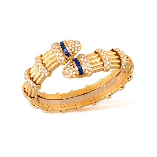 153 - A SAPPHIRE AND DIAMOND BANGLE  Of spring reeded design, with opposing terminals highlighted with bri... 