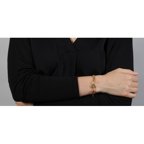 2 - FRED PARIS: A GOLD BRACELET  The chain composed of openwork oval and heart-shaped polished gold link... 