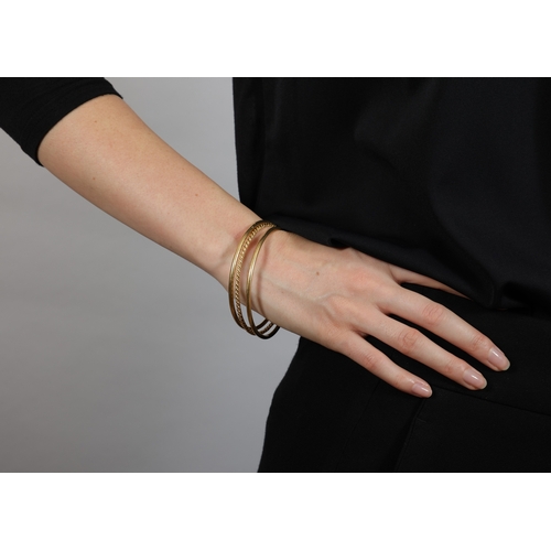 93 - THREE GOLD BANGLES  Composed of two polished gold bangles, in 18K gold, with maker's mark 'Sté HL' a... 