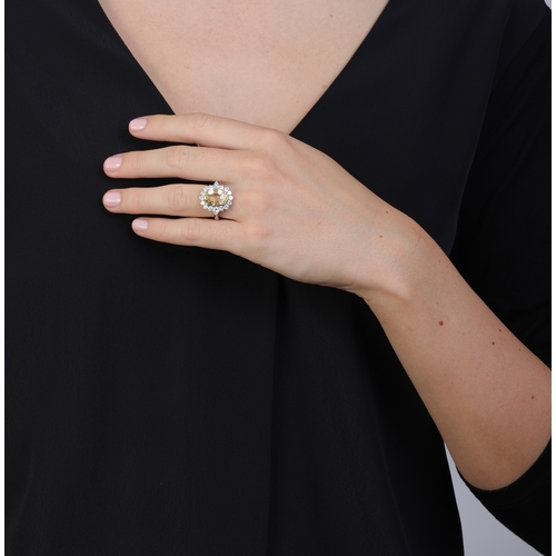 74 - A YELLOW SAPPHIRE AND DIAMOND DRESS RING  Of cluster-design, centring an oval-shaped yellow sapphire... 