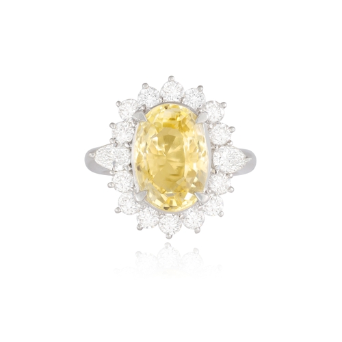 74 - A YELLOW SAPPHIRE AND DIAMOND DRESS RING  Of cluster-design, centring an oval-shaped yellow sapphire... 