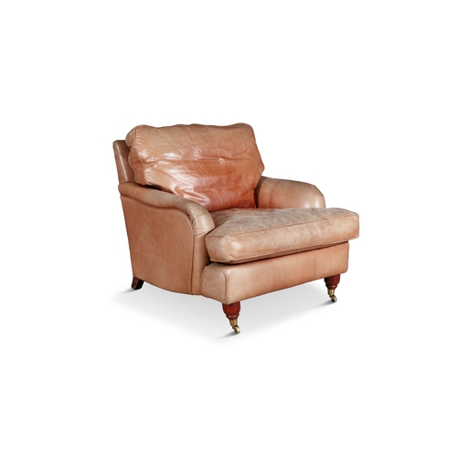 321 - A HOWARD STYLE CLUB ARMCHAIR,   upholstered in tan leather, raised on turned mahogany feet and brass... 