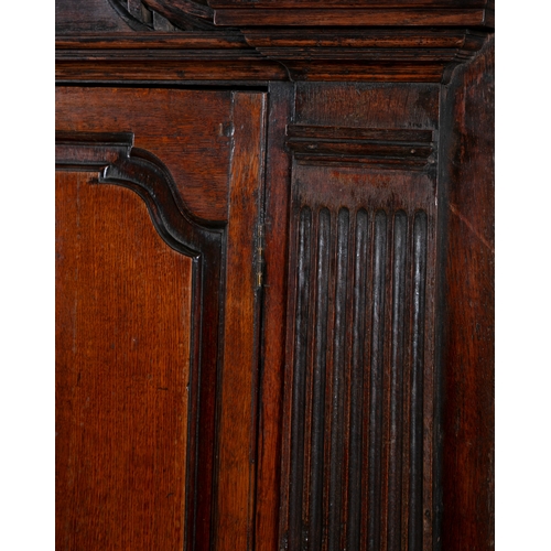 529 - A GEORGE III OAK CORNER CABINET,  the swan neck pediment with rosette terminals, twin fielded panel ... 