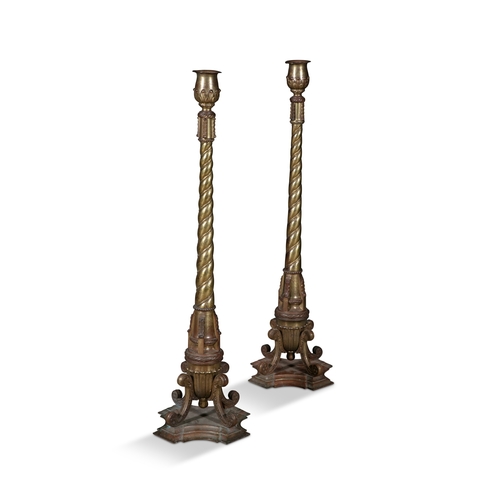 536 - A PAIR OF TALL ECCLESIASTICAL GILT METAL COLUMN CANDLESTANDS,  each with tulip shaped holders, above... 