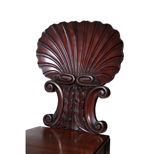 542 - A PAIR OF GEORGE IV MAHOGANY HALL CHAIRS,  with carved scallop shell backs raised on opposing scroll... 