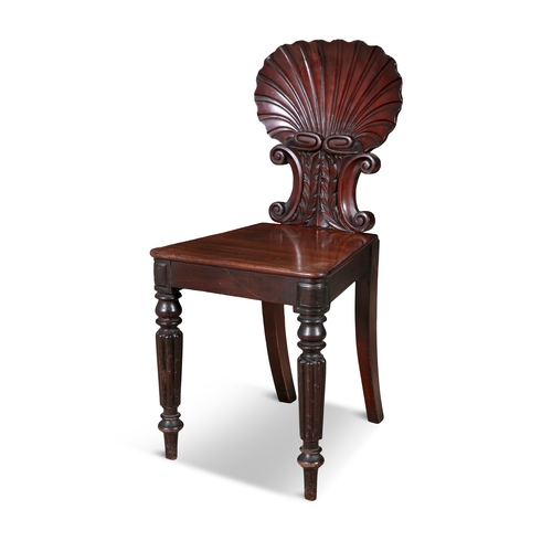 542 - A PAIR OF GEORGE IV MAHOGANY HALL CHAIRS,  with carved scallop shell backs raised on opposing scroll... 