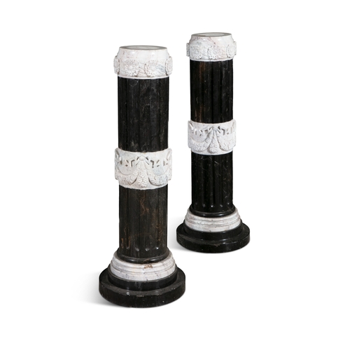 687 - A PAIR OF BLACK MARBLE PEDESTALS OF NEO-CLASSICAL DESIGN SUPPORTING CONFORMING URNS,  the urns carve... 