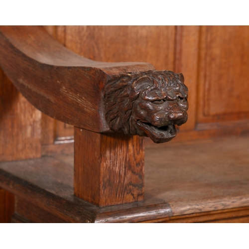 729 - AN IRISH CARVED OAK SETTLE BENCH 19TH CENTURY  the hump four panelled back, the arms carved with lio... 