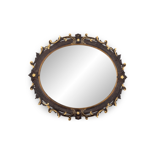 115 - A CONTINENTAL EBONISED AND GILTWOOD OVAL MIRROR,   the frame carved with foliage, C-scrolls and flow... 