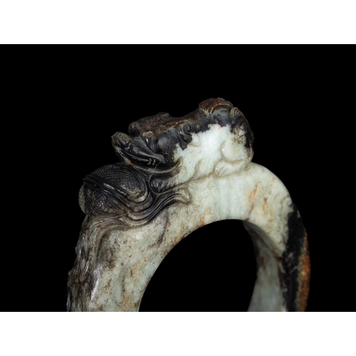 308 - A BLACK AND WHITE JADE RING WITH A PLAYING LION ON THE TOP  明早 黑白玉戏狮环   China, early Ming dynasty.  ... 