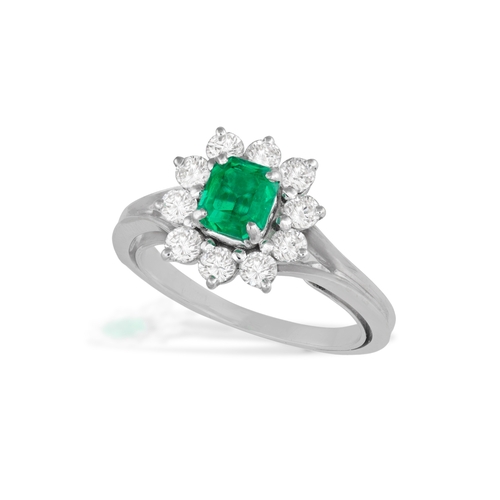 109 - AN EMERALD AND DIAMOND CLUSTER RING  The cut-cornered rectangular emerald, within a four-claw settin... 