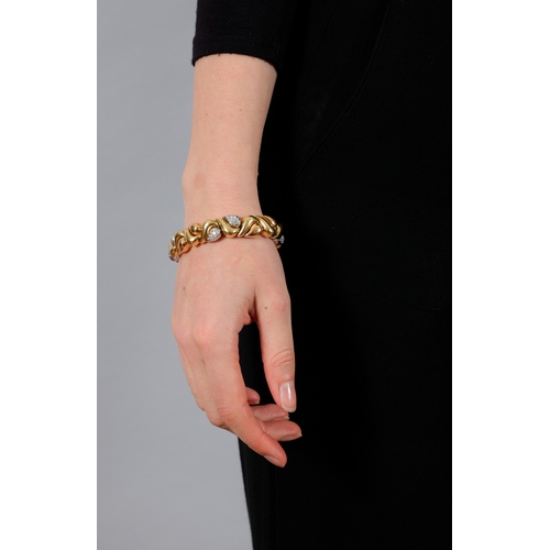 113 - AN 18K GOLD AND DIAMOND BRACELET  Of bi-coloured design, composed of alternating polished scrolled a... 