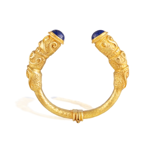 117 - AN ETRUSCAN REVIVAL GOLD AND LAPIS LAZULI BANGLE BRACELET   Of openwork hinged design, each opposing... 