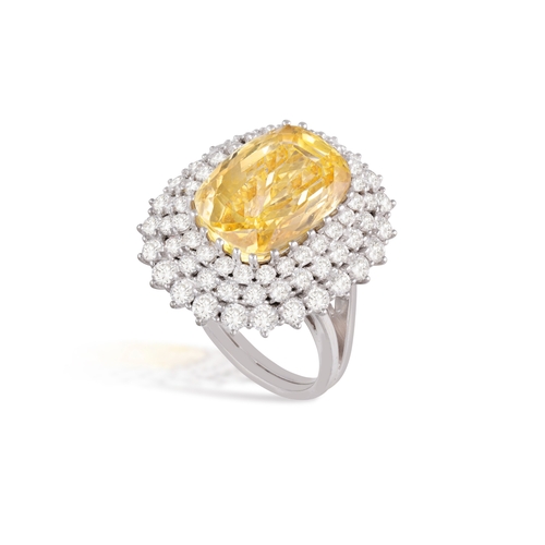 144 - A YELLOW SAPPHIRE AND DIAMOND DRESS RING  Centring an elongated cushion-shaped yellow sapphire weigh... 