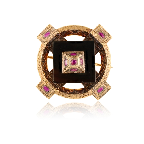 22 - A LATE 19TH CENTURY ONYX AND RUBY BROOCH   Of circular openwork embossed design, centring a square-s... 