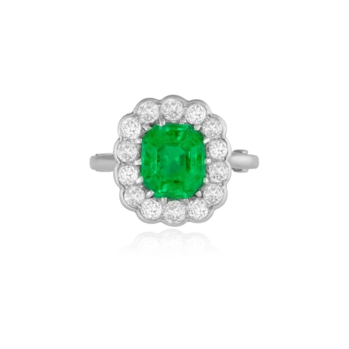 242 - AN EARLY 20TH CENTURY EMERALD AND DIAMOND CLUSTER RING  Set with a cut-cornered rectangular-shaped e... 