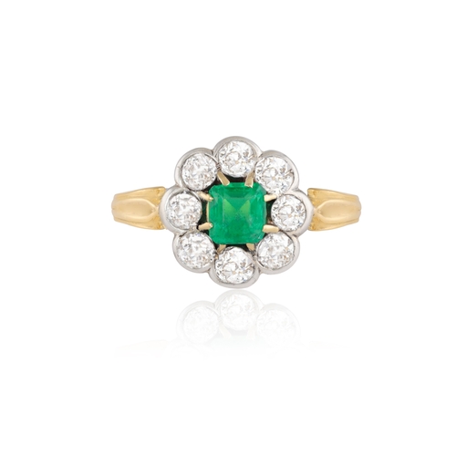 262 - AN EMERALD AND DIAMOND CLUSTER RING  The square-cut emerald set within a eight-claw setting, to a br... 