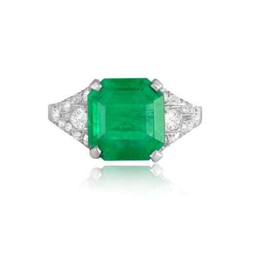 54 - AN EARLY 20TH CENTURY EMERALD AND DIAMOND DRESS RING  The rectangular cut-cornered emerald weighing ... 