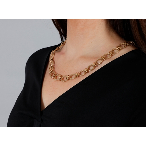 76 - A 9K GOLD NECKLACE  The chain necklace composed of textured gold circular links with X-shaped connec... 