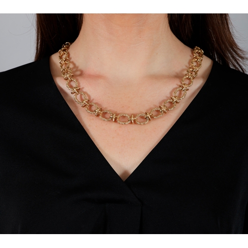 76 - A 9K GOLD NECKLACE  The chain necklace composed of textured gold circular links with X-shaped connec... 