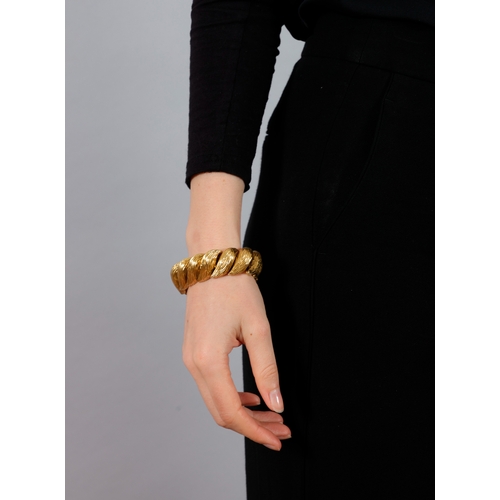 82 - KUTCHINSKY: A GOLD BRACELET, 1963

Designed as a coil of textured gold links with flattened backs, i... 