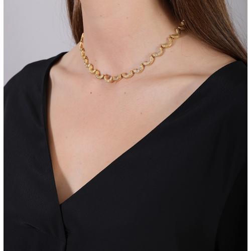 79 - FRED PARIS: A DIAMOND PENDANT NECKLACE, CIRCA 1970  The articulated textured gold chain highlighted ... 