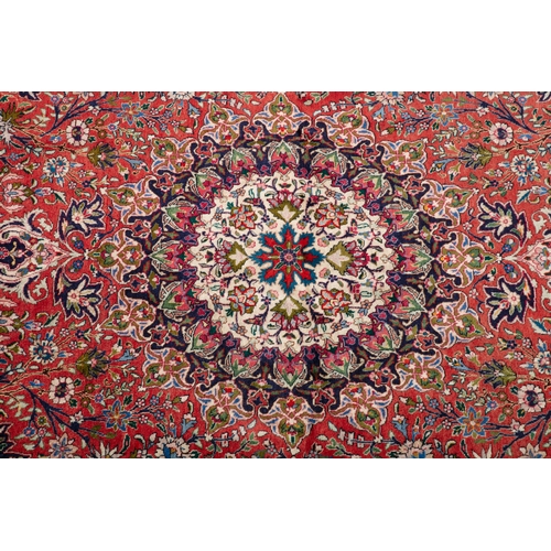 140 - A PERSIAN RED GROUND WOOL CARPET. 400 x 300CM  the large centre field woven with a circular floral m... 