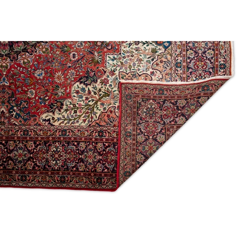 140 - A PERSIAN RED GROUND WOOL CARPET. 400 x 300CM  the large centre field woven with a circular floral m... 