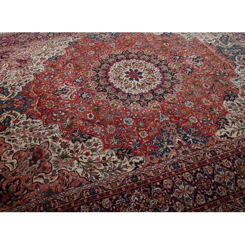 140 - A PERSIAN RED GROUND WOOL CARPET. 400 x 300CM  the large centre field woven with a circular floral m... 