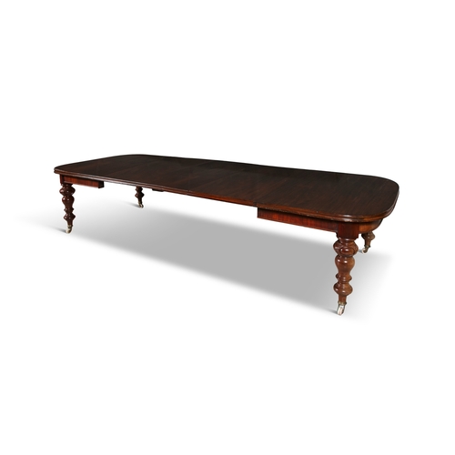 318 - A VICTORIAN EXTENDING MAHOGANY DINING TABLE   with baluster legs brass feet and castors, with three ... 