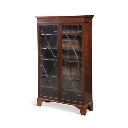 490 - A MAHOGANY TWO-DOOR DISPLAY CABINET  with outset dentil cornice, over twin astragal glazed doors, en... 