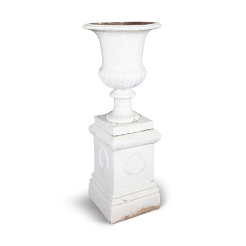 1 - A VICTORIAN WHITE PAINTED CAST IRON GARDEN URN  raised upon a white painted stone plinth of classica... 