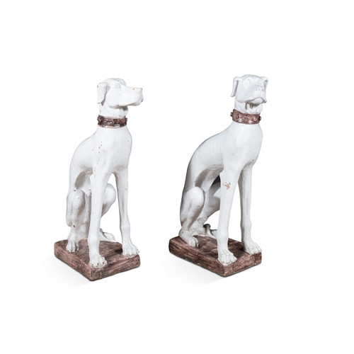 12 - A PAIR OF WHITE GLAZED CERAMIC MODELS OF SEATED DOGS,  the male and female both seated and wearing s... 