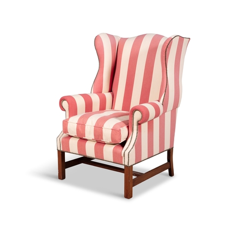 16 - A GEORGIAN STYLE MAHOGANY FRAMED WING BACK ARMCHAIR,  upholstered in a red and cream striped fabric ... 