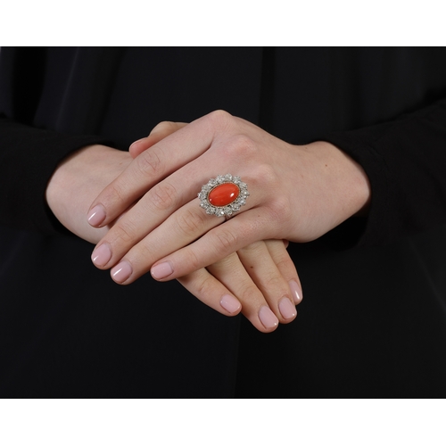 121 - A CORAL AND DIAMOND RING  Set with an oval-shaped coral cabochon, within an old-cut diamond surround... 