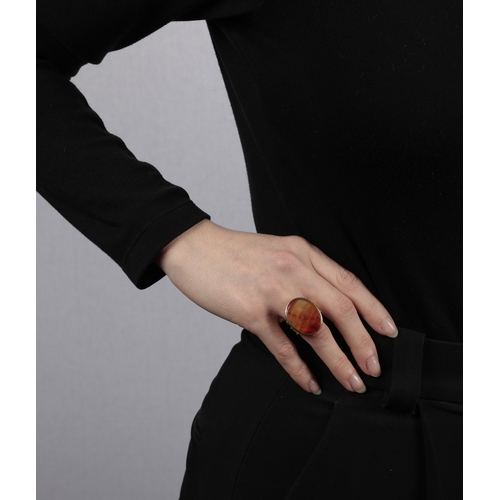 91 - A CARNELIAN RING  The closed-back oval-shaped carnelian, within collet-setting, to a multi-furcated ... 