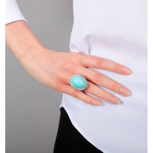 100 - A TURQUOISE AND DIAMOND CLUSTER RING  The oval-shaped turquoise cabochon weighing approximately 40.0... 