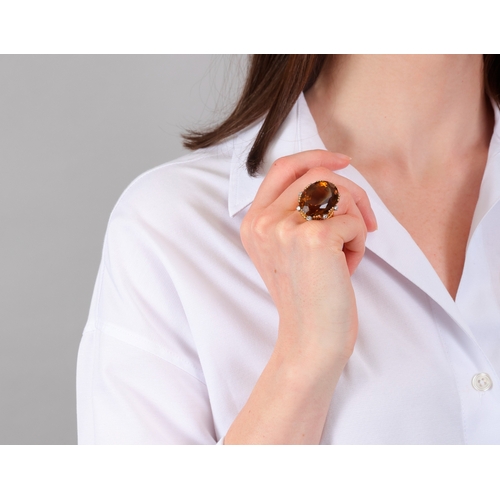 73 - STERLÉ: A CITRINE AND DIAMOND COCKTAIL RING, CIRCA 1950  The raised oval-shaped citrine weighing app... 