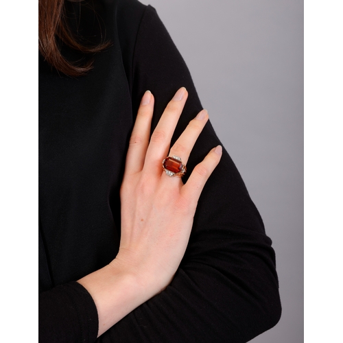 74 - A CITRINE AND DIAMOND DRESS RING, CIRCA 1950  Set horizontally, the cut-cornered rectangular citrine... 