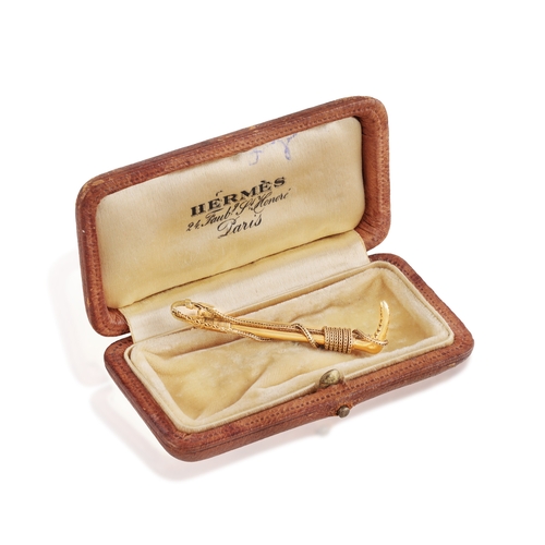 80 - HERMÈS: A GOLD BROOCH, CIRCA 1960  Designed as a riding crop, with ropetwist detailing, in 18K gold,... 