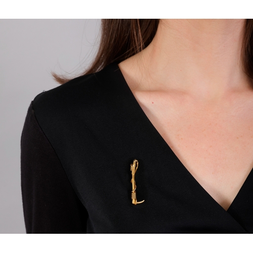 80 - HERMÈS: A GOLD BROOCH, CIRCA 1960  Designed as a riding crop, with ropetwist detailing, in 18K gold,... 