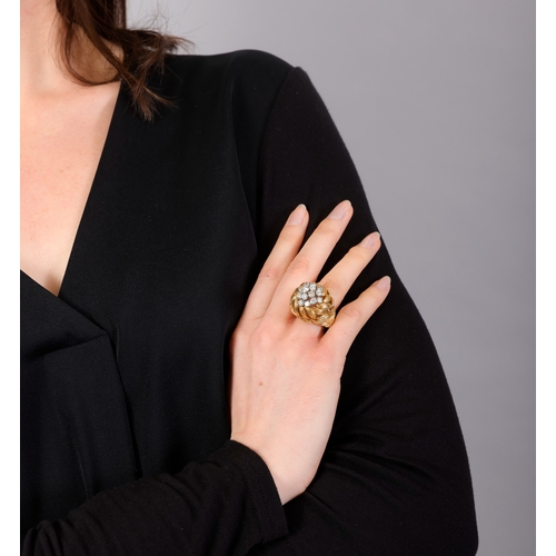 81 - A GOLD AND DIAMOND COCKTAIL RING   The openwork raised mount composed of scrolled textured leaf-shap... 