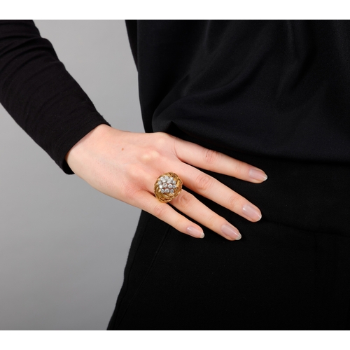 81 - A GOLD AND DIAMOND COCKTAIL RING   The openwork raised mount composed of scrolled textured leaf-shap... 
