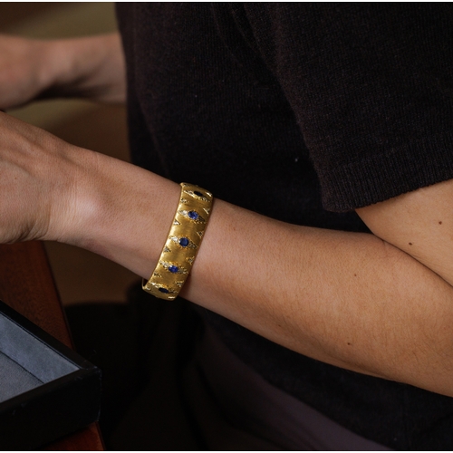 76 - MARIO BUCCELLATI: A BI-COLOURED GOLD AND SAPPHIRE BANGLE, CIRCA 1955  The cuff set with oval-shaped ... 
