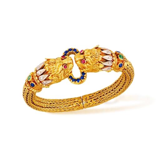 82 - LALAOUNIS: A GOLD AND GEM-SET BANGLE  Of woven foxtail linking, terminating in lion's head motifs at... 