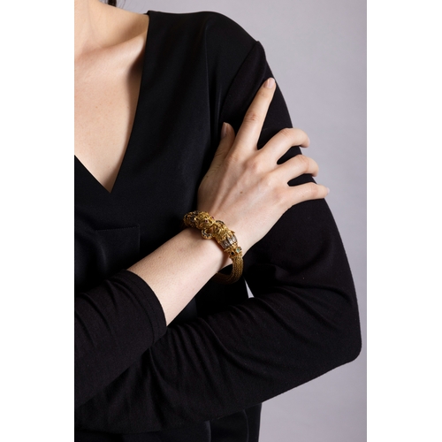 82 - LALAOUNIS: A GOLD AND GEM-SET BANGLE  Of woven foxtail linking, terminating in lion's head motifs at... 